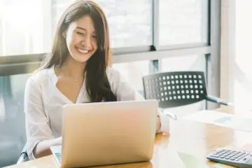 woman smiling and working on her laptop in a conference room