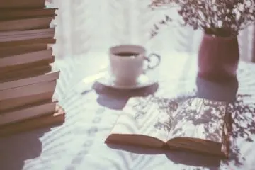 cup of coffee next to a book in a sunlit appartment