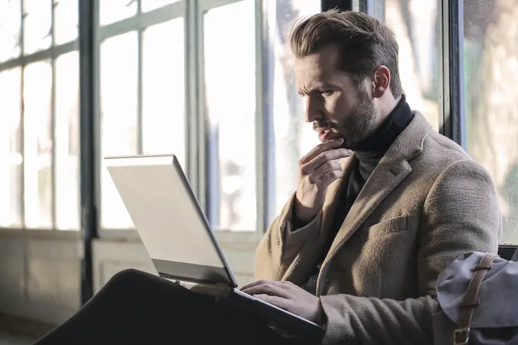 man worryingly looking at laptop and thinking