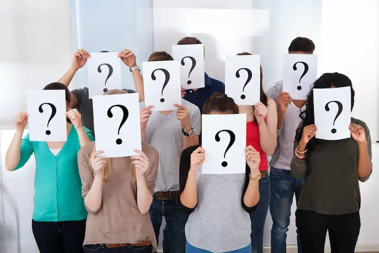 group of people holding question marks in front of their faces