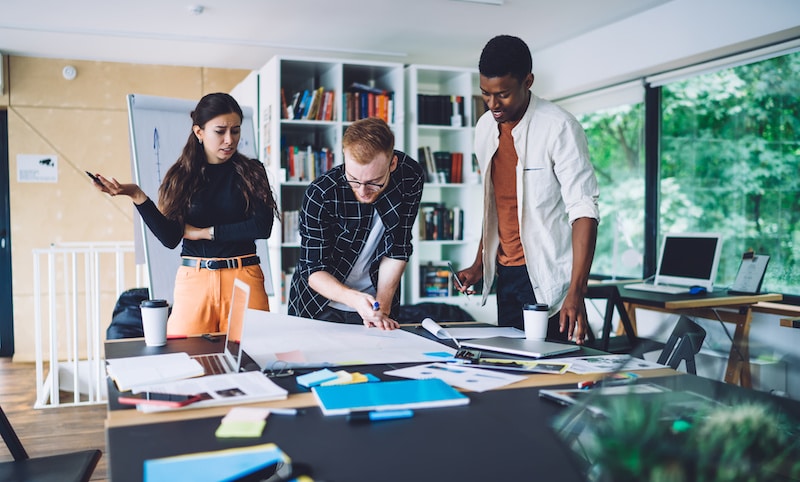 three colleagues working together on a project inside a modern office