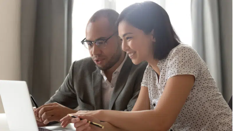 man and woman looking at documents on laptop together