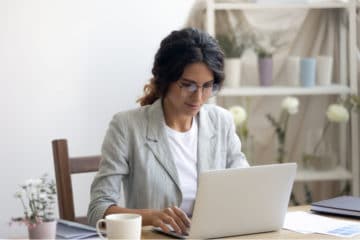 woman in a grey suit jacker working on her laptop