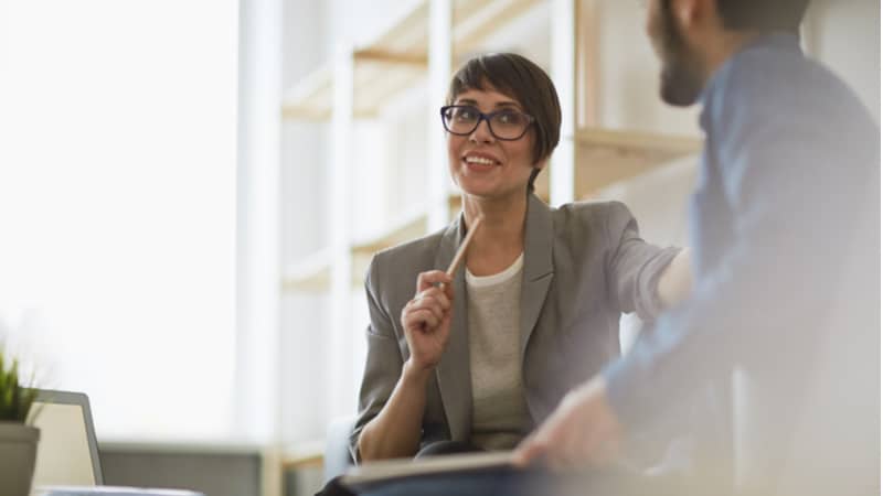 middle aged woman with short hair explaining something to a colleague