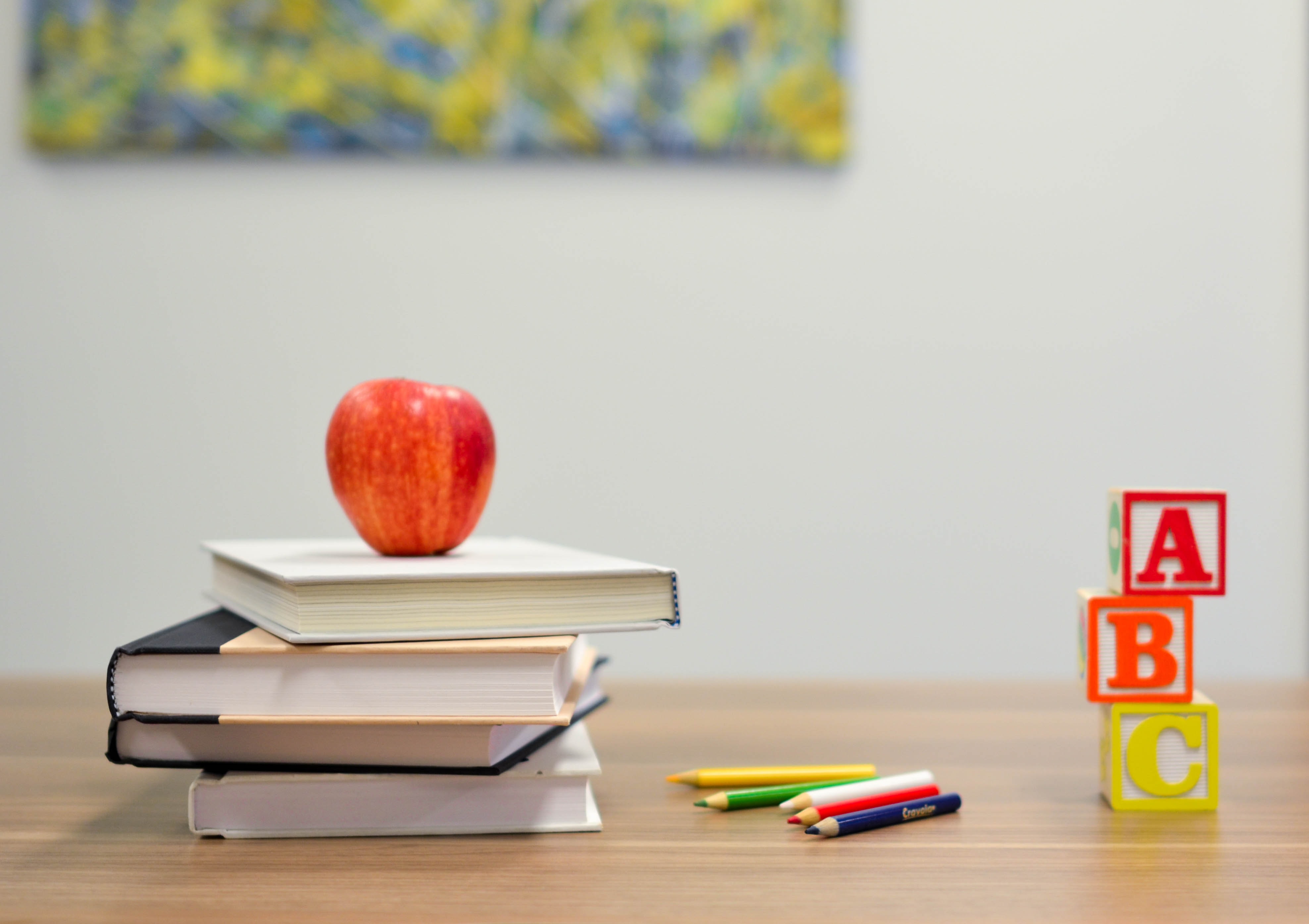 Aple on top of books on a desk in a classroom