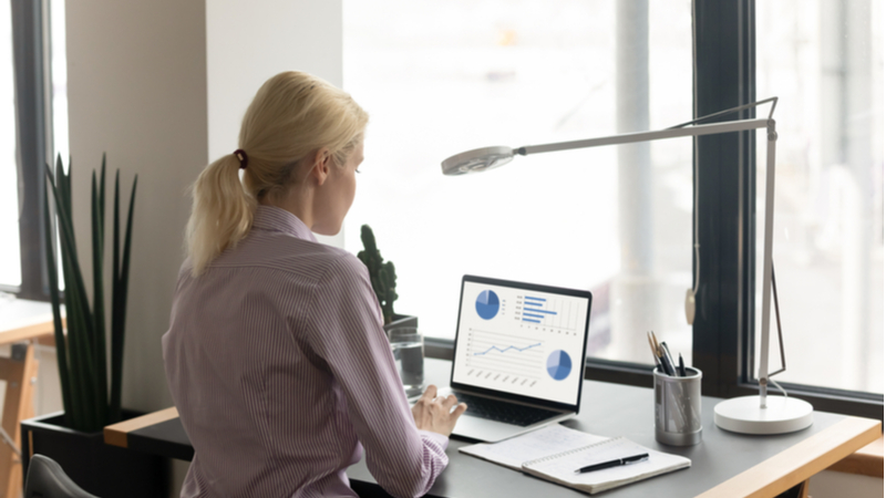 young blonde woman studying on a laptop in her home office