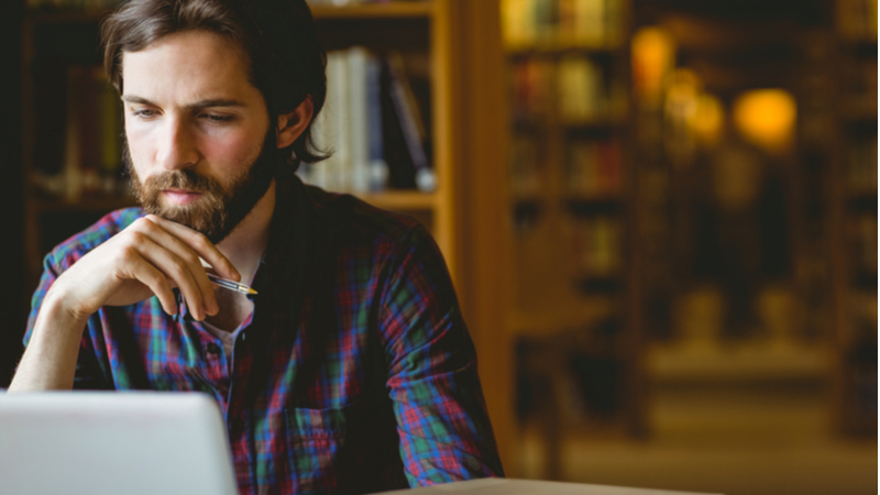 man focused on his laptop while studying in a library