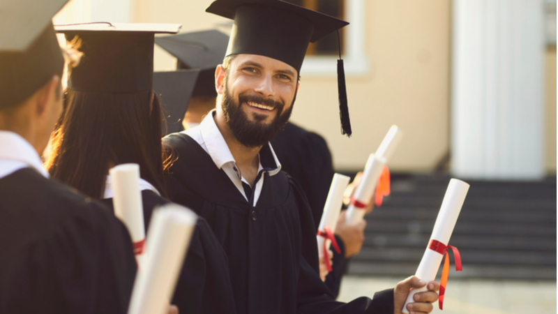 smiling male graduate holding his phd