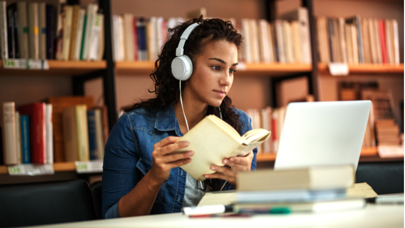 woman with curly hair and headphones studying in the library