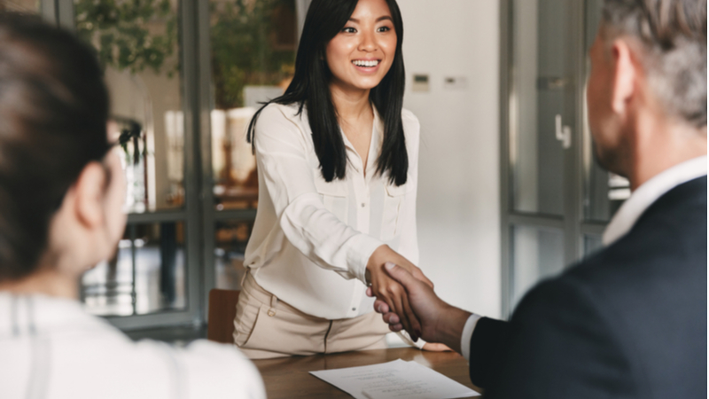 young woman shaking hands with a college professor before ane xam