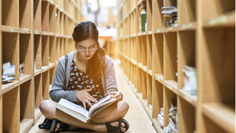 woman sitting on the library floor and studying