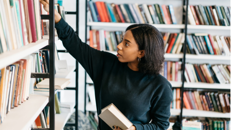 african american woman looking for a book in the library