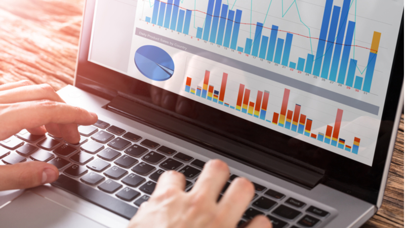 typing on a laptop with charts on it