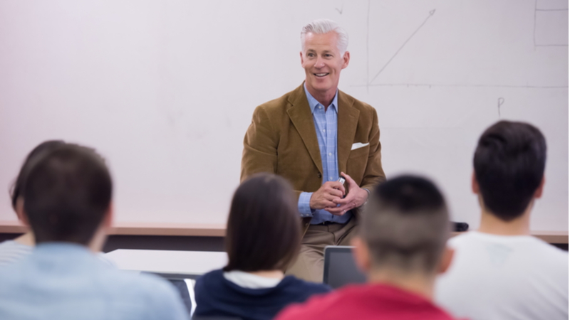 college professor smiling while talking to his students