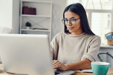 woman with eyeglasses working on her laptop from her home office