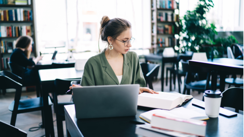 woman with eyeglasses focused on studying in a library