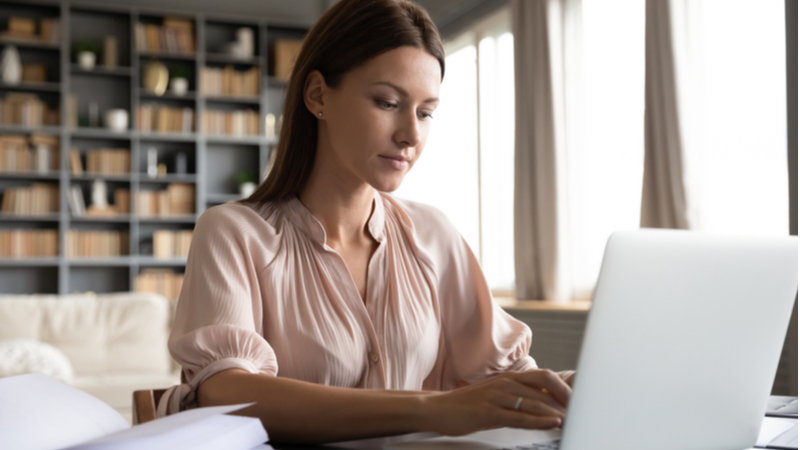 woman typing on her laptop in her bright home office