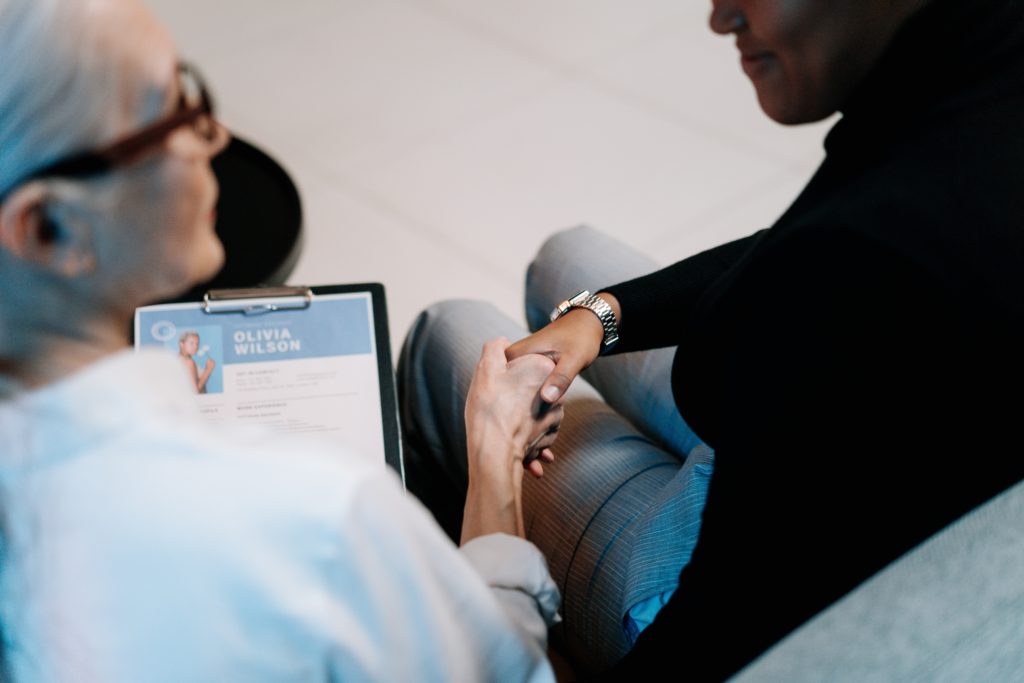 women shaking hands and going through a phd cv resume