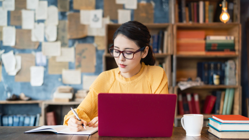 asian grad student taking notes from a laptop