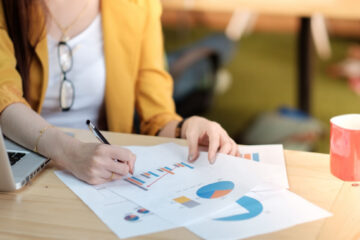 woman in yellow jacket studying analytical charts