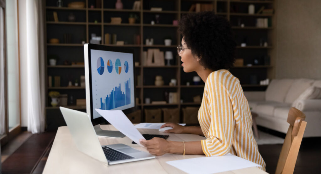 Data Collection woman with curly hair comparing notes in front of computer