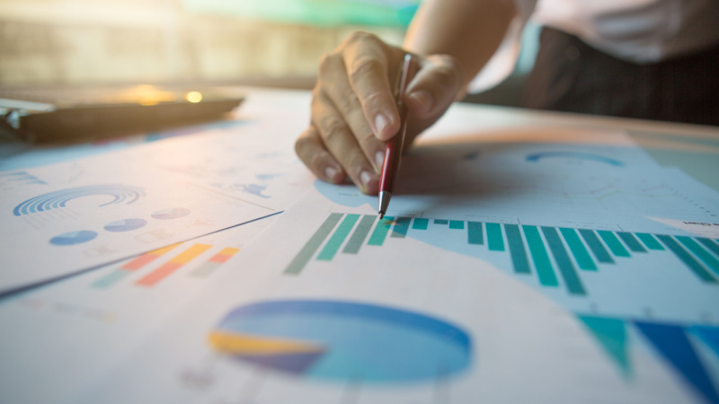 close-up view of a person pointing to statistical charts