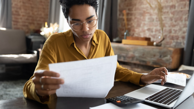 african american woman carefully looking at notes in front of laptop