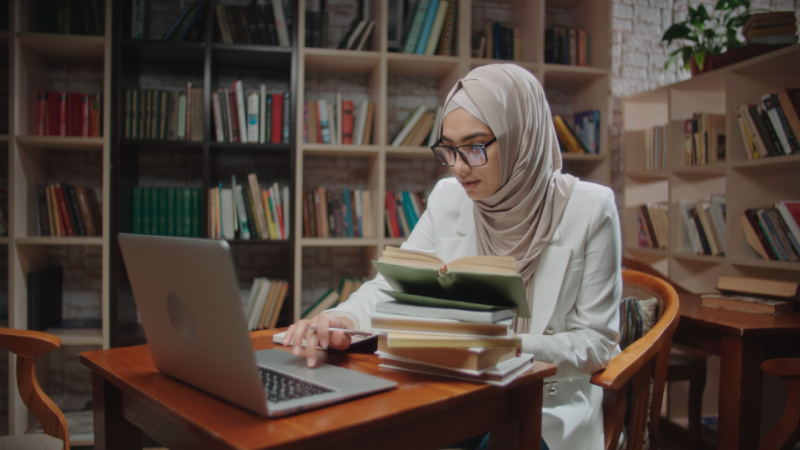 female muslim student studying at a library desk