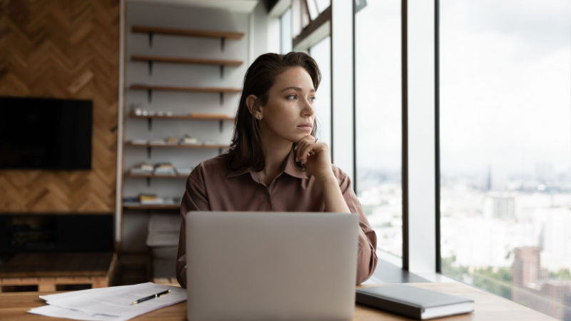 grad student contemplating in front of her laptop and notebook