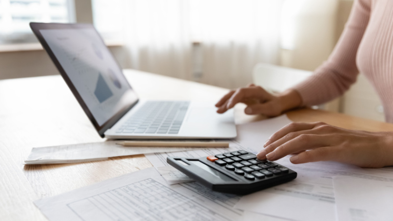 close-up of a woman carefully calculating data in front of laptop