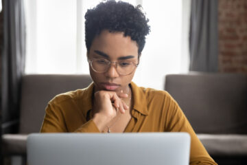 grad student with short hair and glasses focused on her laptop