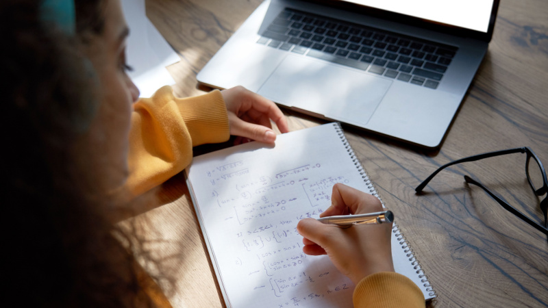 young woman with headphones writing mathematic formulas