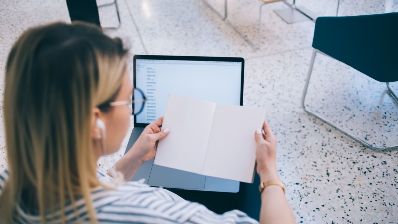 back view of phd student comparing notes to laptop