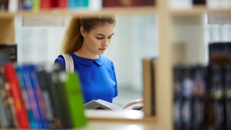 grad student reading a book in a library